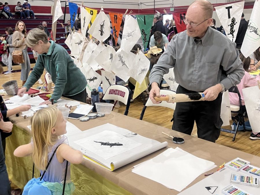 Kids and parents make salamander prints with ink, rolling pins and the help of volunteers.