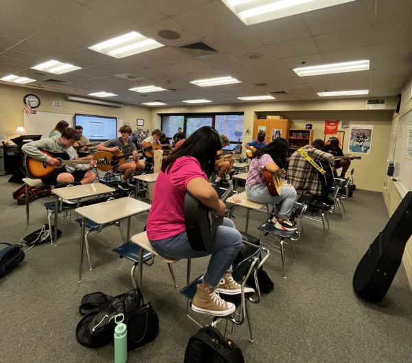 Students in the first-period guitar class tune their instruments and strum as they warm up. 