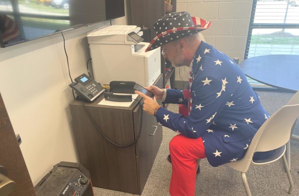 Dr. Joel Henneke controls the music over the intercom during class change. The principal began this game-day tradition last year.