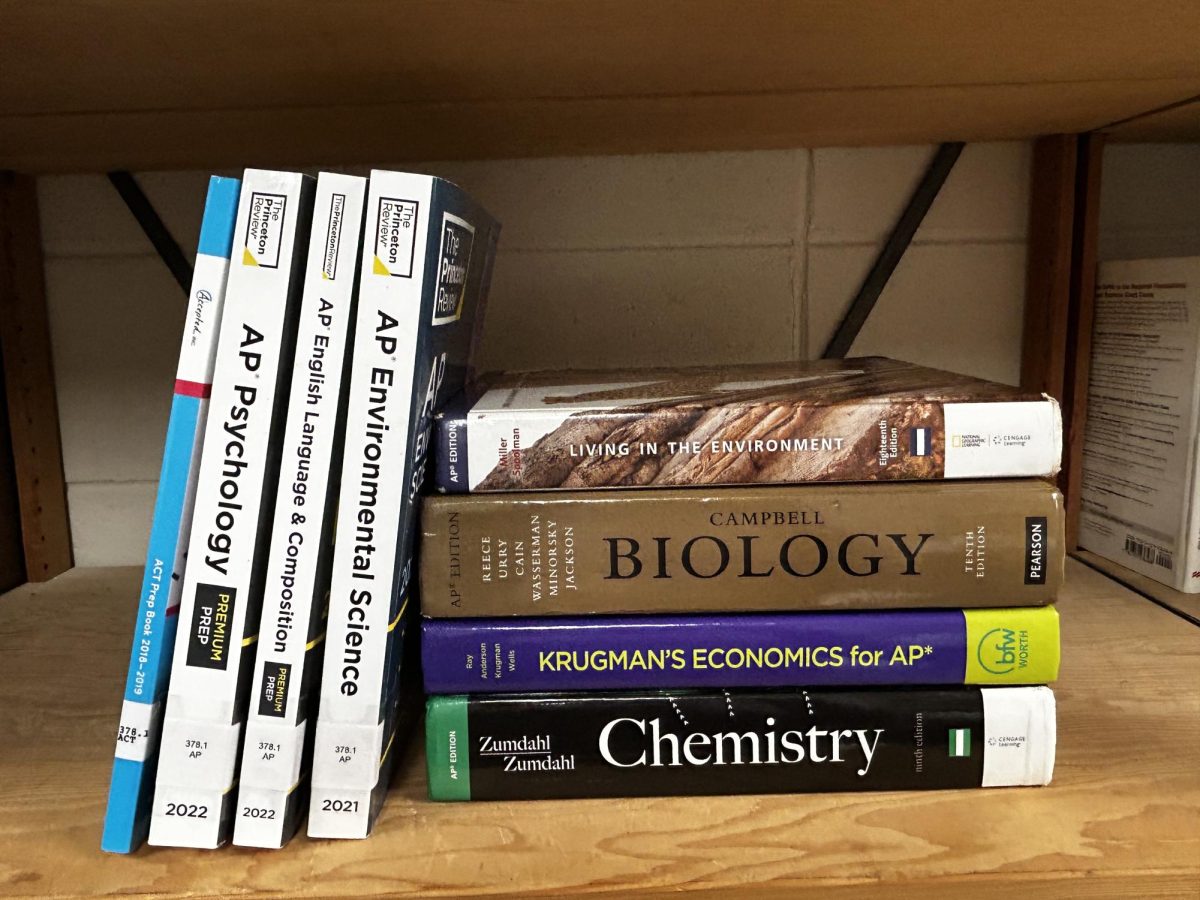 A stack of AP subject textbooks and an ACT prep book sit on a shelf. Many students at Homewood require these books to prepare for their exams.