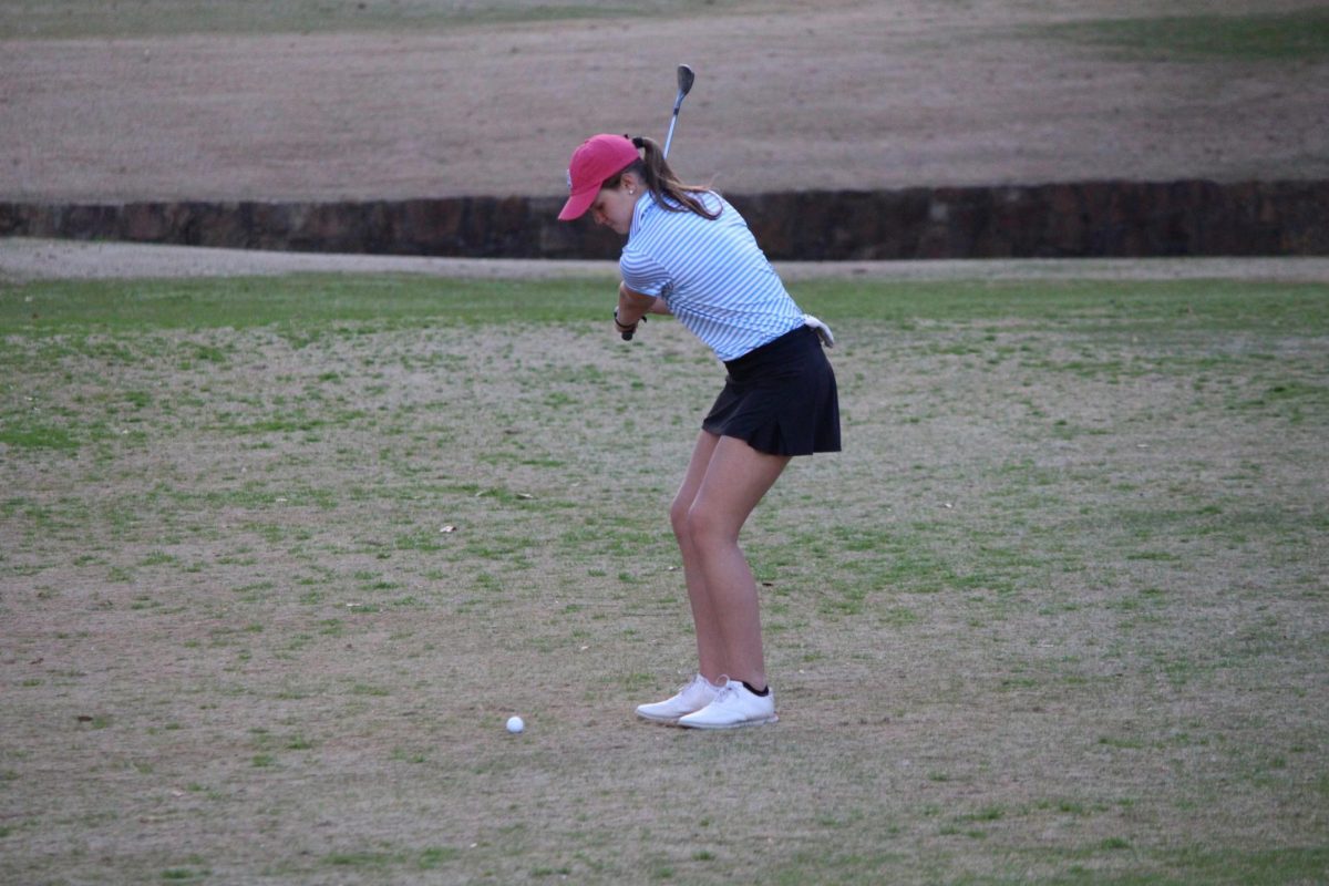 Maddox chipping a shot whilst competing in a golf tournament. 