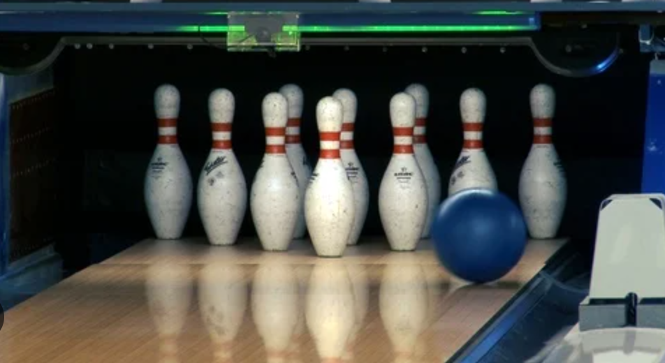 Bowling ball approaches pins at bowling alley. 