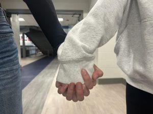 A representation of PDA, students holding hands in the hallway.