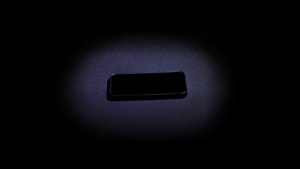 A phone sits on a table as a light shines from above. Homewood's compliance with the FOCUS Act mandates that all students keep their phones in their backpacks from 8 a.m. to 3:10 p.m.