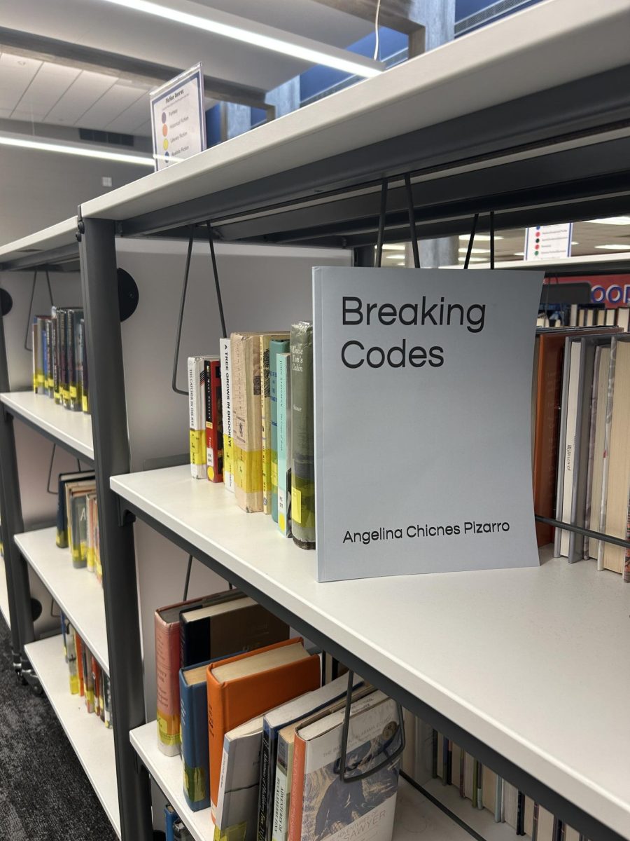 Pizarro's book titled "Breaking Codes" in the library. The book, which focuses on increasing representation in computer science, is listed on Amazon.