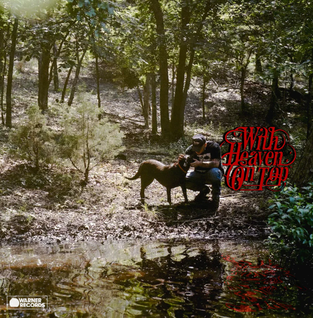 Album cover of "With Heaven on top" which was the first album to reach #1 on the billboard of 2026. Zach Bryan is holding his dog (jack) in front of a creek.
