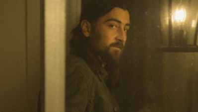 Noah Kahan looks out of a window in cover art for his main track "The Great Divide". The album serves as his second album in four years.